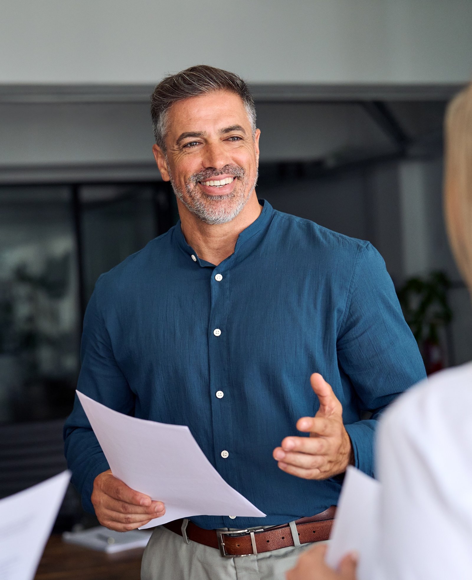 Happy mature executive manager discussing documents with business team.